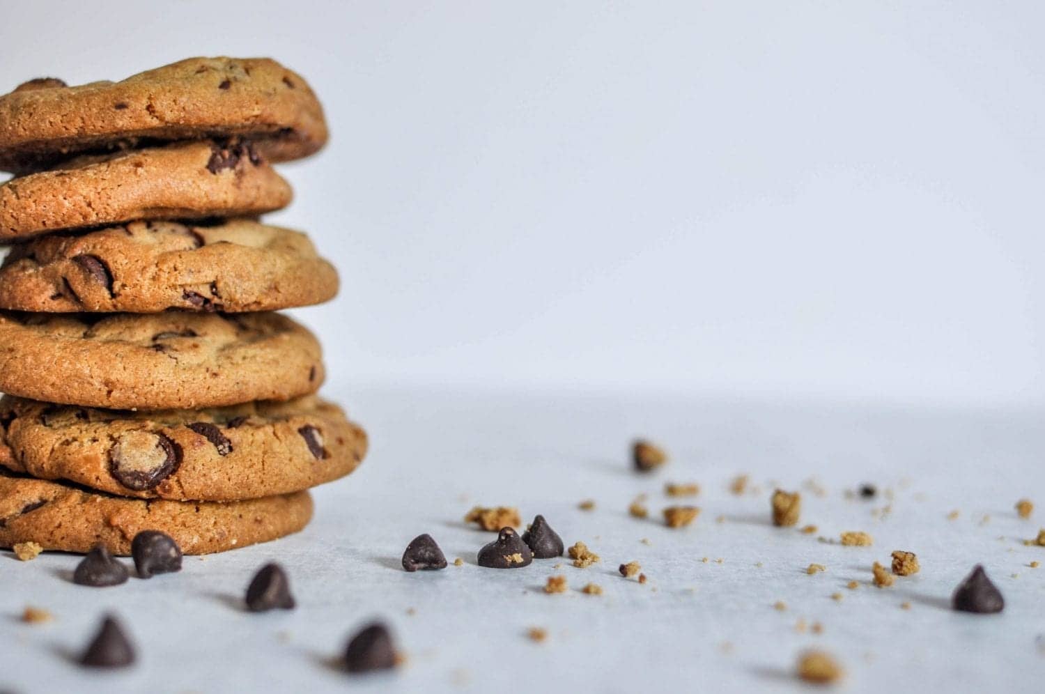 Stack of 6 weed cookies on a white table with chocolate chips